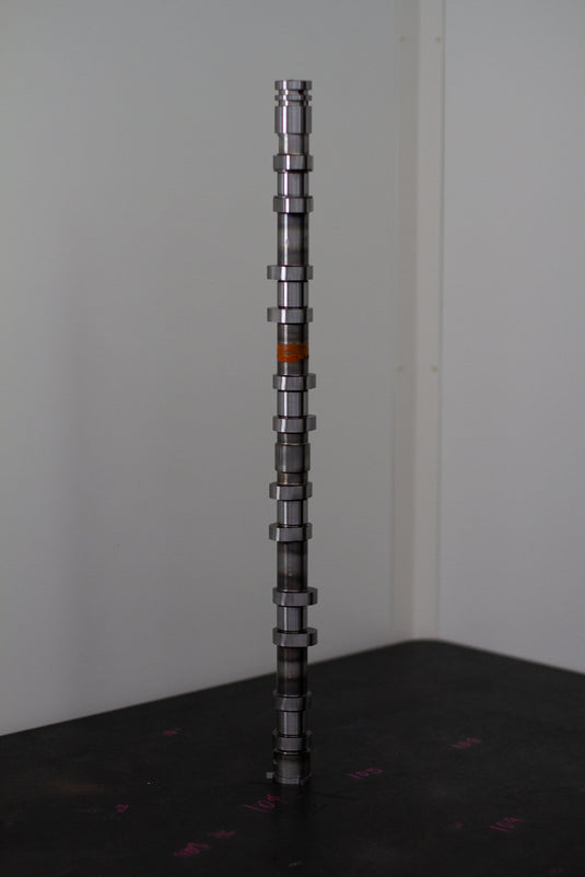 Camshaft on a black surface with a white background