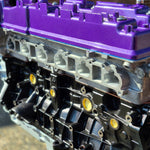 complete engine on display with purple rocker cover with brick background
