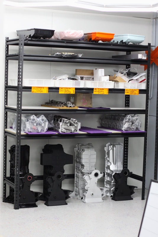 various engine arts including sumps and timing covers on black shelves